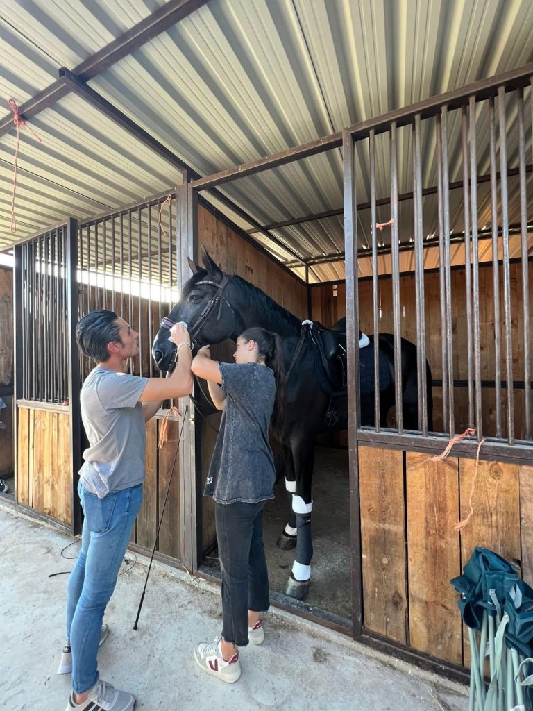 dos personas ensillando caballo
